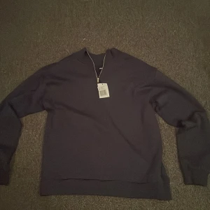 Marinblå half zip tröja från RYVLS - Snygg marinblå tröja från RYVLS med half zip-dragkedja i halsen. Tröjan har en stilren design med lång ärm och ribbade muddar. Perfekt för dig som gillar en clean och modern look.