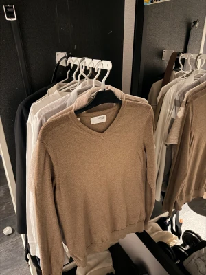 Beige v-ringad tröja från Selected Homme ( HELT NY ) - Snygg beige v-ringad tröja från Selected med lång ärm och mjuk känsla. Perfekt för dig som gillar stilrena och enkla plagg. Passar dig som vill ha en klassisk look. Tröjan är helt ny och aldrig använd!