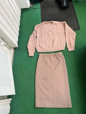 Beige långkjol från Vero Moda - Säljer en beige långkjol från Vero Moda storlek S med snyggt stickat kabelmönster. Kjolen är rak i modellen och har en mjuk, stickad känsla som gör den superbekväm. Perfekt att matcha med en stickad tröja för en chill och trendig look.  från SHEIN  storlek S 