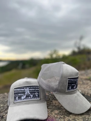 CR7 Grå velvet Trucker keps [HELT NY] - Snygg grå keps med mesh på sidorna och bak, perfekt för dig som gillar sportig stil. Framtill finns en svartvit patch med Cristiano Ronaldo som ger kepsen en unik vibe. Skärmen är böjd och materialet känns mjukt och bekvämt. Passar dig som vill sticka ut med en cool accessoar.