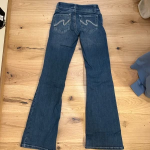 Lågmidjade bootcut jeans  - Snygga blå jeans med bootcut passform och broderade detaljer på bakfickorna. Låg midja 