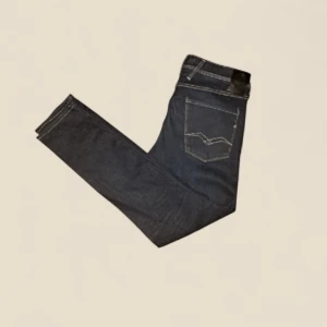 Mörkblå Replay Anbass jeans - Snygga mörkblå jeans från Replay, modell Anbass. Klassisk femficksdesign med kontrastsömmar och läderpatch bak i midjan. Jeansen har en smal passform och är tillverkade i mjukt denimtyg som sitter skönt hela dagen. Original pris:1499. Mitt pris: 399