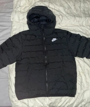 Svart pufferjacka från Nike - Svart pufferjacka från Nike. Jackan är i mycket bra skick och har inga repor, jackan är köpt för 1600 och har använts i 3 månader. Passar perfekt till vinterns kalla dagar