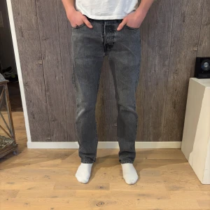 Levi’s 501 – Straight svarta jeans - Ikoniska Levi’s 501 i svart denim – originalet när det kommer till tidlös stil. Straight passform med button-fly.  ✔️ Storlek: 30/32 ✔️ Modell: 501, Zip/Button-fly (klassisk 501-stil) ✔️ Färg: Svart denim ✔️ Skick: Dåligt