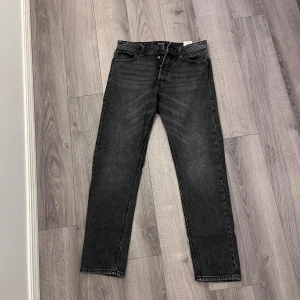 Svarta loose fit jeans från Jack & Jones - Säljer ett par svarta jeans från Jack & Jones i modellen Loose Chris. Jeansen har en loose passform med raka ben och klassisk femficksdesign. Materialet är jeans och färgen är mörkgrå/svart med lätt tvättad look. Perfekta för dig som gillar avslappnad stil.