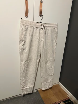Beiga linnebyxor - Säljer ett par beiga linnebyxor från Zara i storlek L. Byxorna har elastisk midja med snörning, sidfickor och två bakfickor. De är raka i modellen och tillverkade i ett luftigt linnematerial, perfekta för en chill och avslappnad stil.