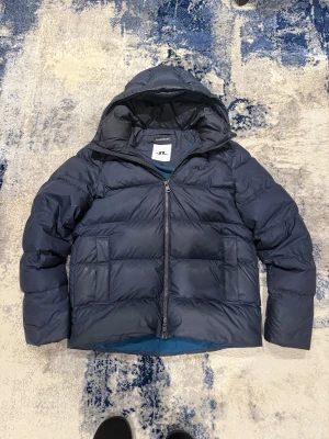 Blå j.lindeberg vinterjacka - Säljer denna riktigt snygga och populära vinterjackan från j.lindeberg. Storlek L, han på bild är 185cm 75kg. Inga defekter! Pris kan diskuteras vid snabb affär! 