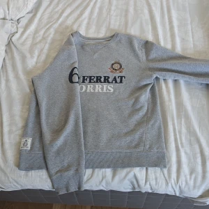 Grå sweatshirt från Morris Cap Ferrat - Grå sweatshirt från Morris Cap Ferrat med broderade detaljer och tryck i marinblått, vitt och rött framtill. . Snyggt broderat emblem på bröstet och patch vid nederkanten. Perfekt för dig som gillar klassisk stil. Pris ej ner hugget i sten Kommer dessutom med en gåva 🫣