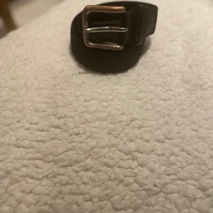 Svart skärp från Jack & Jones - Snyggt svart bälte från Jack & Jones med klassiskt silverfärgat spänne. Bältet har detaljer i skinn och en stilren design som passar till jeans eller chinos. Perfekt accessoar för att lyfta din outfit. Lite rostig tyvärr men annars jätte fräsch 