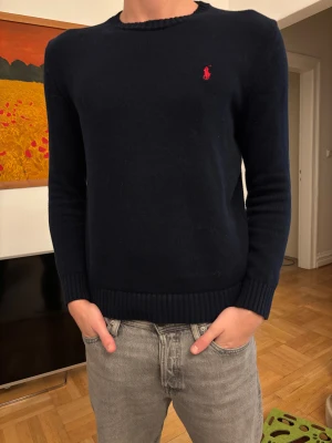 Svart Ralph Lauren stickad - Svart stickad tröja från Polo Ralph Lauren i storlek M. Klassisk rund hals och långärmad modell med röd broderad logga på bröstet.  Otroligt fint skick och knappt använd. Passar mig bra som är 180 70kg. Hör av er vid intresse🏌️