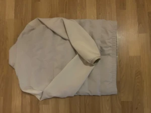 Beige pufferjacka från Zara - Snygg beige pufferjacka från Zara med stilren design och raka linjer. Jackan har ståkrage, dragkedja framtill och två sidofickor. Materialet är mjukt och quiltat, perfekt för kyliga dagar. Passar dig som gillar minimalistisk och clean look.