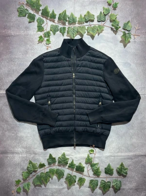 Moncler Tricot Black Label i Navy Storlek M [ÄKTA] - 🎨 Färg: Mörkblå / Navy 📏 Storlek: Medium (M) ♻️ Skick: 10/10 – minimalt slitage, inga fläckar eller skador 🧵 Material: Quiltad lättviktsfront + mjuka, stickade ärmar och rygg ✨ Detaljer: • Hybridmodell med dun/quiltad front och tygärmar • Hög krage • Tvåvägsdragkedja framtill • Två fickor med dragkedja • Moncler-logga i tonal mörkblå färg på vänster ärm • Stilren och modern passform, perfekt som lätt jacka eller mellanlager ‼️ Skickas dagen efter köpet genomförs! ‼️