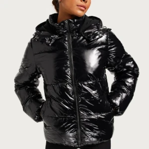 Svart glansig pufferjacka från nelly  - Säljer en svart glansig pufferjacka med huva och dragkedja framtill från Nelly. Köpt förra vintern, inga defekter. Pris kan diskuteras😇💗