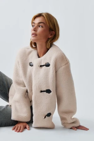 Beige teddyjacka med svarta detaljer - Säljer en beige teddyjacka med coola svarta knäppningar framtill. Säljer då jag inte använder längre, men den är så snygg och håller värmen! 