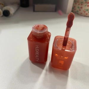 Huda Beauty Watermelon Pop Liquid Blush - Flytande rouge i färgen Watermelon Pop från Huda Beauty. Ger en fräsch och naturlig rodnad med en saftig, vattenmelonröd ton. Perfekt för att skapa en glowig look. Swatch har gjorts en gång på handen annars oanvänd. Nypris: 359kr FINNS FLERA FÄRGER AV SAMMA I MIN PROFIL. 