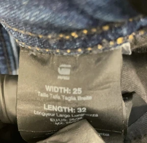 Blå bootcut jeans från G-Star RAW - Snygga blå jeans från G-Star RAW i bootcut-modell med klassisk femficksdesign och låg midja. Jeansen har en mörk tvätt och är tillverkade i stretchigt denim för skön passform. Perfekta för dig som gillar retrovibbar och vill ha ett par jeans med lite extra attityd.