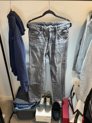Grå loose fit jeans från H&M - Säljer ett par gråa jeans från H&M med loose fit och justerbar midja. Klassisk femficksmodell med raka ben och knappstängning fram. Jeansen har en snygg tvättad look och passar dig som gillar avslappnad stil.
