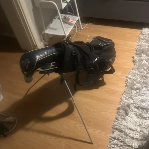 Spalding Blue Bull Golfklubbor med väska - Komplett set med Spalding Blue Bull golfklubbor och praktisk bärväska med benstativ. Klubborna inkluderar järn 5, 6, 9 och loft wedge, samt driver med skydd. Viss kosmetisk slitage syns på klubborna, men allt är i gott bruksskick och redo för spel. Får även med bollar.