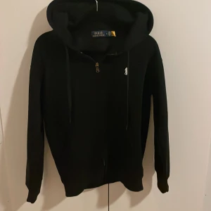 Svart hoodie från Polo Ralph Lauren - Svart zip hoodie från Polo Ralph Lauren! Väldigt snygg och skönt material. Väldigt fint skick och bra kvalitet! Storlek S ✨Hör av er vid frågor ✨