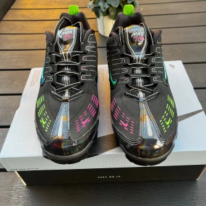 Nike Air Vapormax 360 Svarta sneakers - Nike Vapormax 360 sneakers i svart med neonrosa och neongröna detaljer, samt iriserande effekter på ovansidan och hälen. Skorna har snörning, platt sula med synliga luftkuddar och rund tå. Märket syns tydligt på plösen, innersulan och yttersulan. 