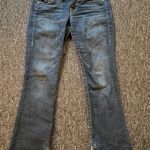 True Religion bootcut jeans blå, stl 27 - Köpta här på plick och dom är sparsamt använda. Dom är Limited Edition därav priset, men går att diskutera vid snabbt köp! Defekten är att längden är klippt samt lite fläckiga nedtill. Tveka inte på att höra av dig om du har funderingar kring något! Mått: Innerbenslängd- 71cm Grenmått- 20cm Midjemått- 37cm rakt över 💗