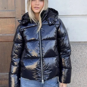 Svart glansig pufferjacka med huva - Säljer min svarta Nelly jacka, den är jätte varm och perfket till vintern men obs den kan vara lite trög att stänga men det är inget som har stört mig!