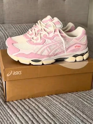 ASICS sneakers i rosa och vitt - Säljer ett par snygga ASICS sneakers i ljusrosa och vitt med mesh och mockadetaljer. Skorna har rund tå, platt sula och snörning i både rosa och vitt. Perfekt för dig som gillar sportig stil och vill sticka ut med färg. Ikonisk ASICS-logga på sidan och tungan.