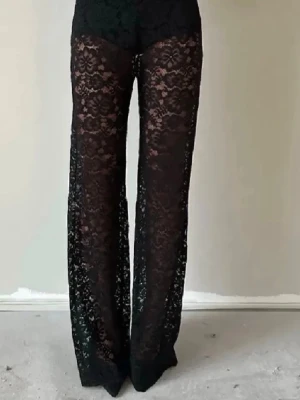 Svarta spetsbyxor med blommönster - Säljer ett par svarta byxor i transparent spets med blommigt mönster. Byxorna har hög midja och är vida i benen, vilket ger en riktigt snygg och trendig look. Perfekta för dig som vill sticka ut med en unik stil. Aldrig använda. Byxorna är i en stor S i storlek men passar bra på mig som har xs också