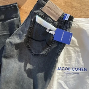 Jacob Cohën Nick Slim - Exklusiva Jacob Cohën-jeans ’Nick slim’ som är helt nya, med alla originallappar, tillbehör och detaljer kvar. Medföljer gör även den ikoniska Jacob Cohën-scarfen samt den lyxiga signaturparfymen som kommer med vid nyköp – vilket gör detta till ett komplett premiumset.