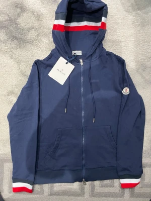 Moncler zip Hoddie  - Helt ny moncler zip Hoddie som aldrig använts då den passar inte mig därför säljer jag den, skriv privat för mer bilder fick inte plats med alla här men kan skicka mer bilder som visar Hoddins detaljer. Priset kan självklart diskuteras😊 Liten i storlek så rekommenderar den till storlek S (small)