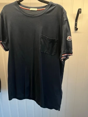 Moncler T-shirt  - Säljer denna Moncler T-shirt då den inte kommer till någon användning. Mycket fint skick. Storlek XL men skulle säga att den passar L. Nypris ca 2500 kr. Hör av dig om du har några frågor!