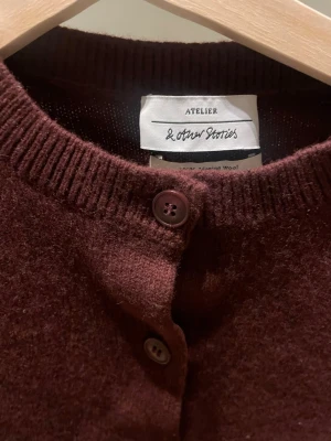 Vinröd kofta från & Other Stories - Snygg vinröd kofta från & Other Stories Atelier med rund hals och knappar hela vägen framtill. Tillverkad i mjuk merinoull som känns skön mot huden. Perfekt att slänga över en t-shirt eller ha som lager under jackan. Långärmad och klassisk passform.