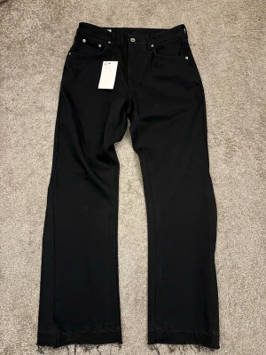 Svarta Flare Jeans - Svarta jeans från Zara med rak passform och fransade benslut för en cool vibe. Knapp och dragkedja fram. Materialet är jeans och färgen är helsvart. Perfekt för dig som gillar stilrena och trendiga byxor.