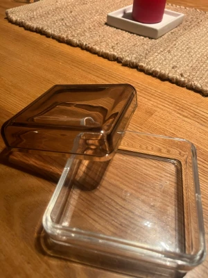 Genomskinlig ”låda” (mörk tint) för smyckesförvaring - Fyrkantig ”låda” med lock för att förvara smycken. Genomskinlig (något mörkt tintad), i material av plast/glas.