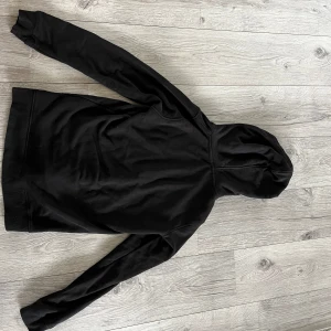 Svart hoodie från Polo Ralph Lauren med björntryck - Svart hoodie från Polo Ralph Lauren med klassiskt björntryck på bröstet. Tröjan har huva och en stor magficka framtill. Perfekt för en avslappnad och stilren look.