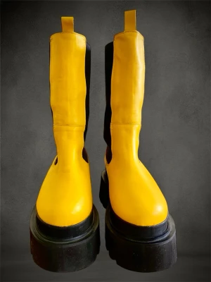 Gula chunky chelsea boots i äkta skinn - Säljer ett par riktigt statement gula chelsea boots med svart resår på sidorna och grov platåsula. Skorna är tillverkade i skinn och har rund tå samt rejäla dragflikar upptill. Perfekta för dig som vill sticka ut med färg och chunky vibes. Märket är Yellows och de är från Italien. De är mjuka och sköna inuti. Mycket hög kvalitet. De är nya. Jag har bara använt dem i ca 2 timmar. Jag har opererat min ena fot och kan tyvärr inte använda dem mer. Nypris 1800kr. Kartong medföljer. 