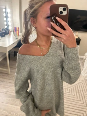 Grå stickad offshoulder-tröja - Mysig grå stickad tröja med offshoulder-look och långa ärmar. Tröjan har en loose passform. 