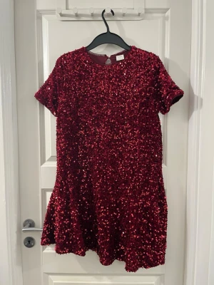 Vinröd paljettklänning från Zara - Säljer en vinröd kortklänning från Zara, täckt med glittriga paljetter. Klänningen har rund hals, korta ärmar och ett lätt utställd nederdel. Perfekt för dig som vill sticka ut med en glittrig look. Materialet är polyester och klänningen har en mjuk insida. Använt bara en gång 