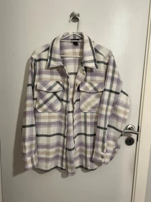 Rutig kappa från Lindex - Rutig kappa i färgerna vit, svart och lila. Oanvänd! Passar även M 