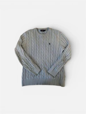 Ljusgrå stickad tröja från Polo Ralph Lauren - Säljer en ljusgrå stickad tröja från Polo Ralph Lauren med klassiskt kabelstickat mönster och rund hals. Tröjan har långa ärmar och en liten broderad logga på bröstet. Perfekt för dig som gillar stilren och tidlös design.