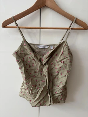 Blommig linnetopp från & Other Stories - Säljer en grön linnetopp från & Other Stories med små rosa blommor och smala axelband. Jättesöt till våren 