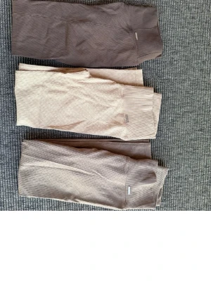 Ribbade leggings från Aim'n i beige och brun - Säljer tre par snygga leggings från Aim'n i olika beige och bruna nyanser. Två par är ribbade och ett par har en strukturerad yta. Alla har hög midja och stretchigt material som sitter skönt. Perfekta för chill eller träning.