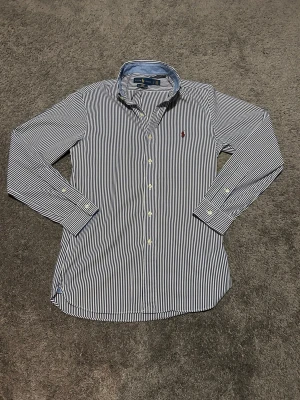 Ralph Lauren skjorta storlek S  - Riktigt bra skick och sparsamt använd. Klassisk röd Ralph Lauren logga. Blå och vit randig 