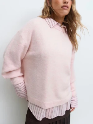 Ljusrosa stickad tröja  - Supermjuk ljusrosa stickad tröja från Gina med rund halsringning och avslappnad passform. Tröjan har ribbade muddar vid ärmslut och nederkant, perfekt att styla över en skjorta för en trendig lager-på-lager-look.