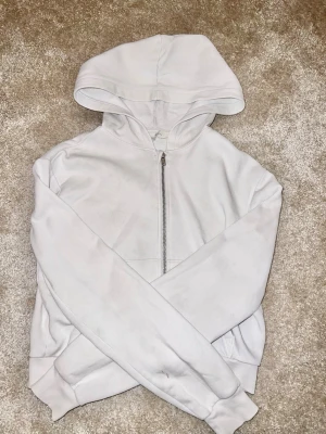 Vit hoodie - Säljer en vit hoodie från H&M den är i bra skick men har en liten fläck som går bort med klorin eller vanish. Använd fåtal gånger. Den är ganska kort i modellen. Storlek 158/164. Hör av er om eventuella frågor🙌🏼