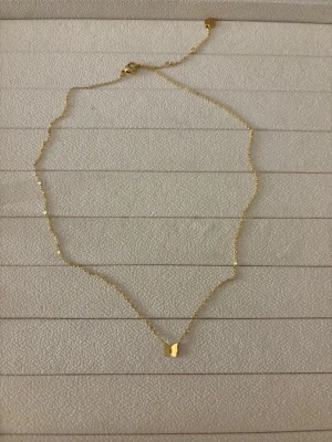 Muli collection - halsband - Guldigt halsband från Muli collection med en fjäril. Helt nytt. ’BUTTERFLY NECKLACE’ på hemsidan, tillverkat i vattentåligt 18k guld PVD pläterat stål och har en längd på 37,5 cm + 5 cm för justerbar passform.