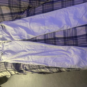 Vita byxor från Junkyard, loose fit - Säljer ett par beiga byxor från Junkyard med rak och loose passform. Byxorna har klassisk femficksdesign och bälteshällor. Perfekta för dig som gillar en avslappnad stil och vill sticka ut med ljusa byxor.