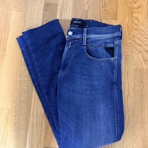 Blå Replay Anbass jeans, storlek 32 - Säljer ett par snygga blå Replay Anbass jeans i storlek 32. Klassisk femficksmodell med normal passform och raka ben. Jeansen är tillverkade i stretchigt denim för extra komfort och har diskreta slitningar för en cool look.