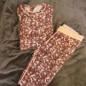 Underställ från Kari Traa - Supersnyggt underställ från Kari Traa i brun och rosa med blommigt och fågelmönster. De har en bred, ljusrosa resår med logga och är tillverkade i mjukt syntetmaterial som andas. Perfekta för träning eller chill, med slim passform och hög midja.