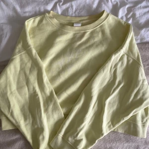 Ljusgul croppad tröja från H&M - Superfin ljusgul croppad tröja från H&M med rund halsringning och långa ärmar. Tröjan är i mjuk bomull och har en relaxed fit som är perfekt för vår och sommar. Enkel och stilren design som är lätt att matcha.